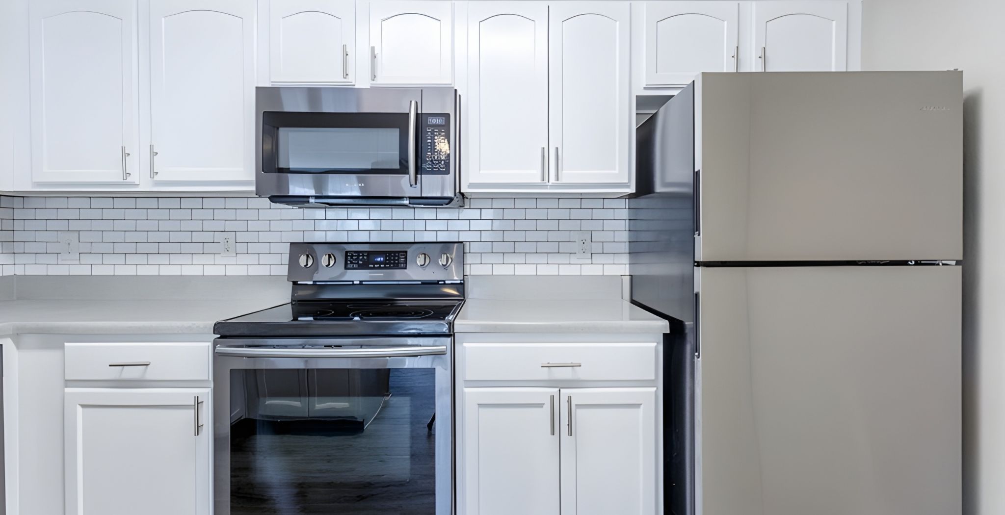 Modern kitchen with stainless steel appliances, white cabinets, and a white subway tile backsplash.